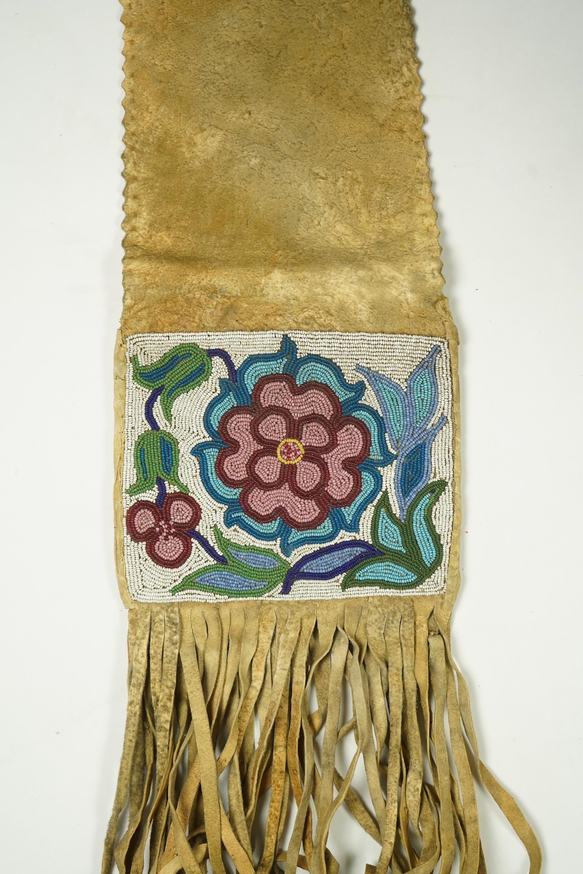 A late 19th century Native American beaded and fringed hide bag. With two different decorative beaded panels front and back. Possibly Cree. 60cm long. Condition - both panels of beadwork are in good condition. The hide a